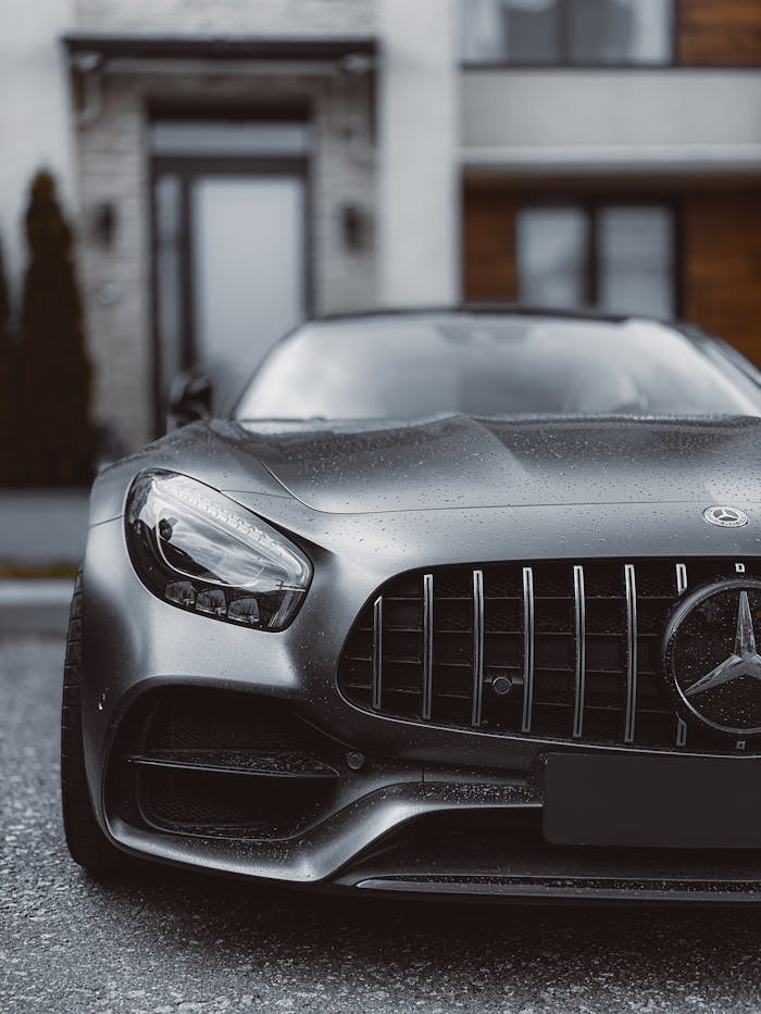 Close-up of a sleek Mercedes Benz car front, showcasing luxury design in an urban background.
